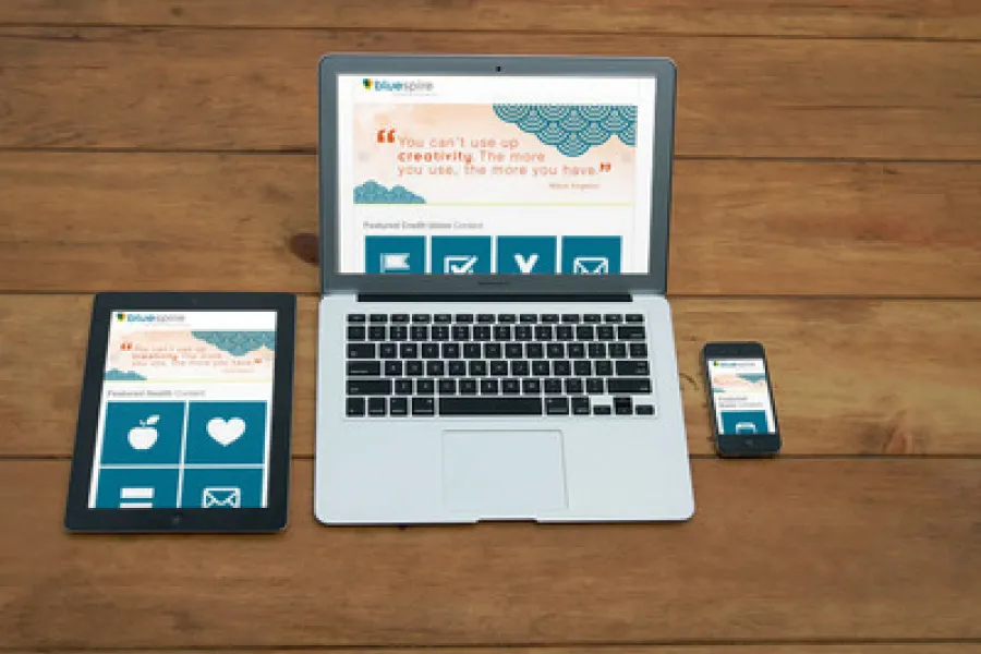 A desk with a computer, tablet, and mobile phone showing the Bluespire Holiday website.